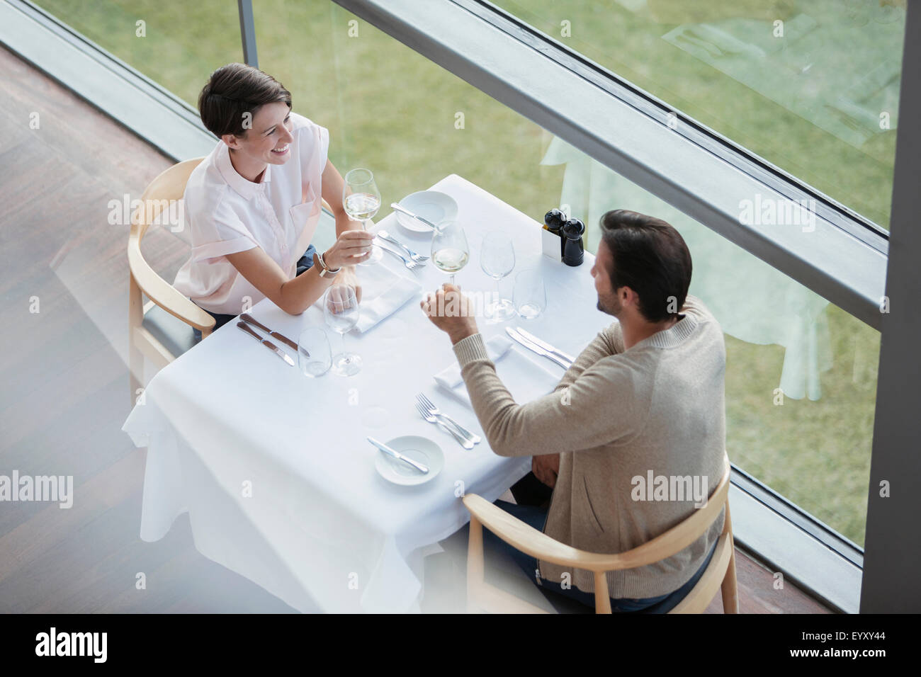 Paar, toasten Weingläser an Restauranttisch am Fenster Stockfoto
