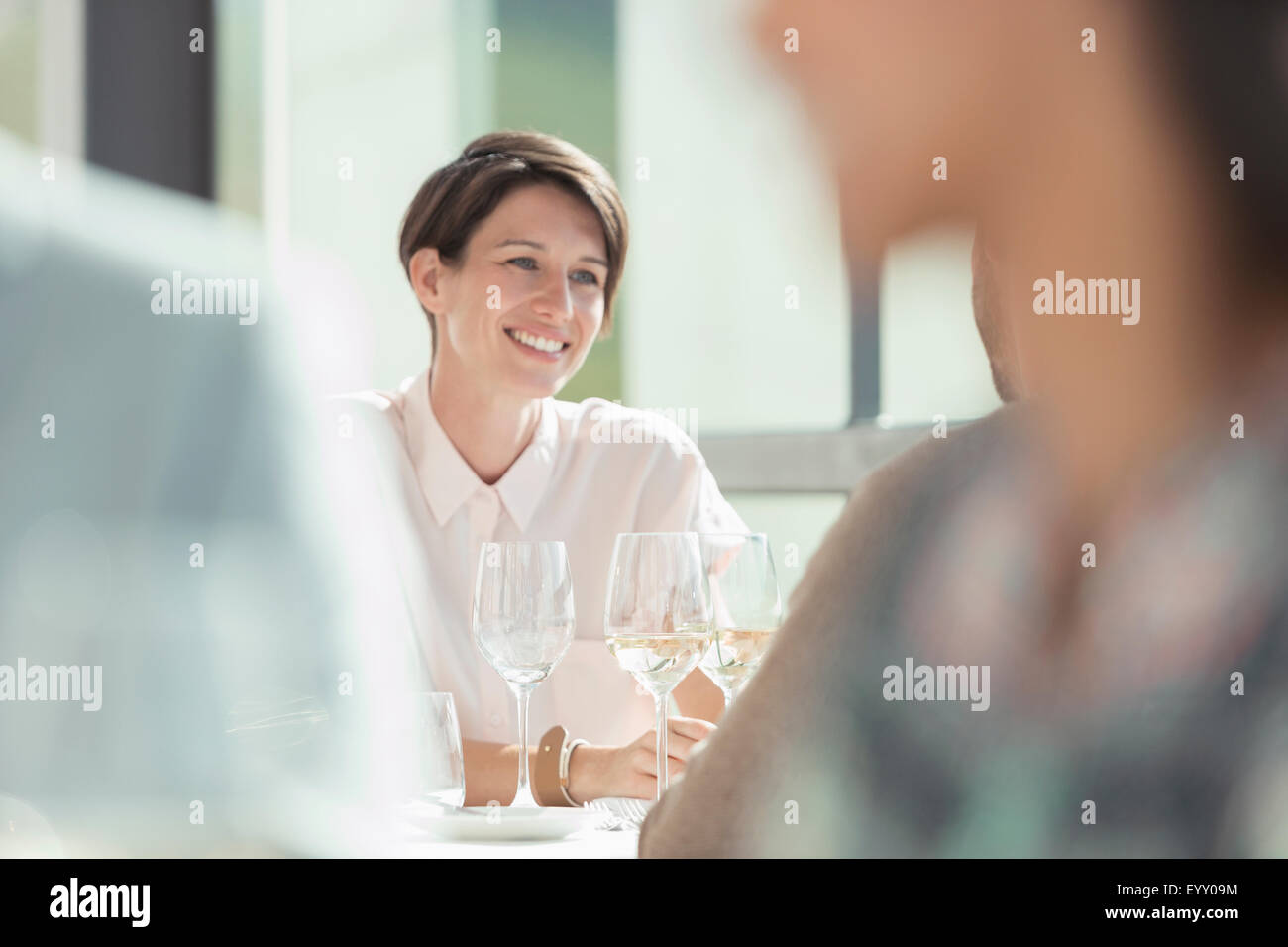 Lächelnde Frau trinken Weißwein im sonnigen restaurant Stockfoto