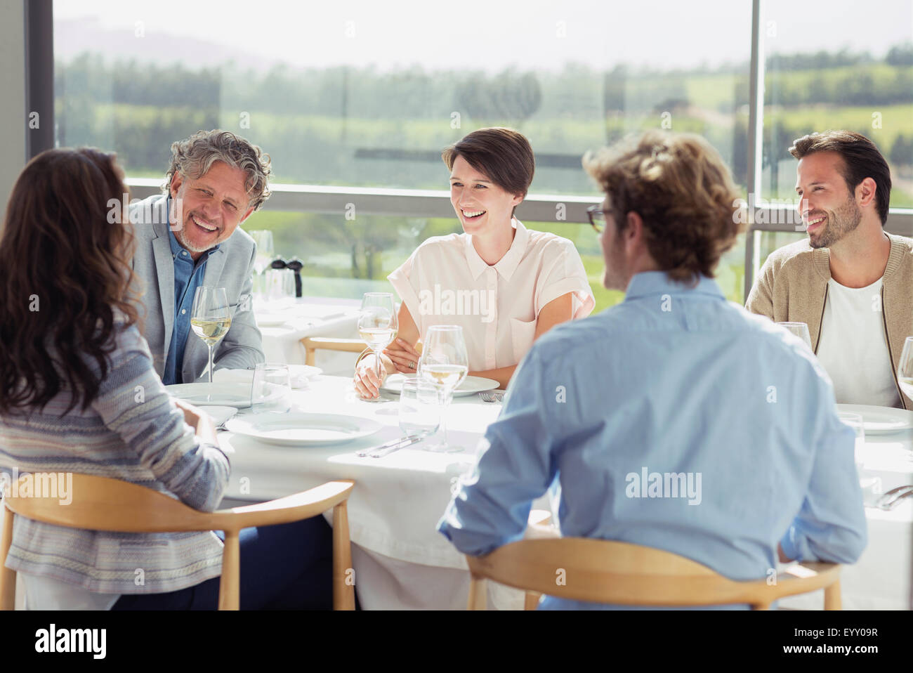 Freunde trinken Weißwein und an sonnigen Restauranttisch reden Stockfoto