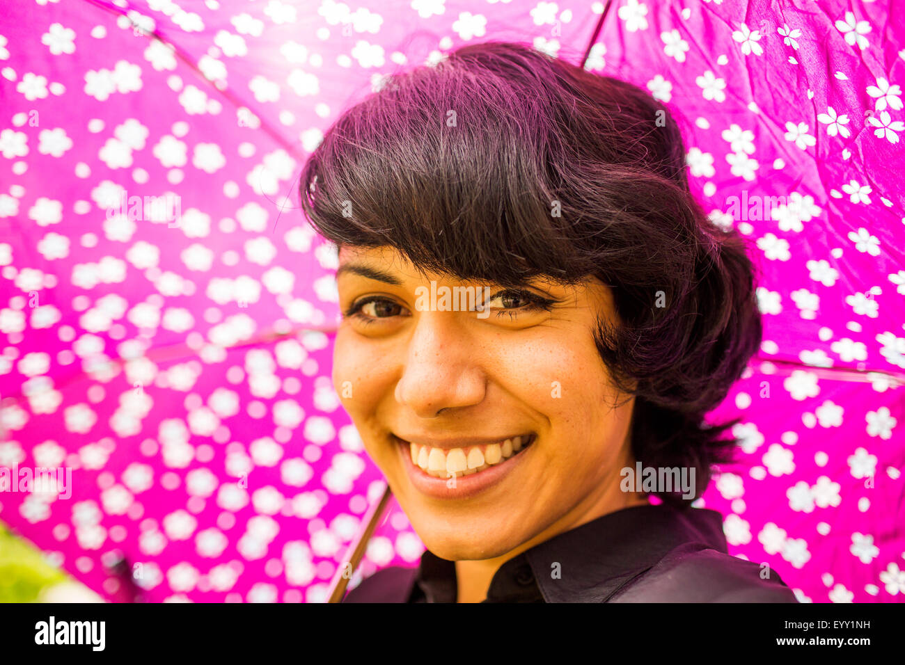 Lächelnd Hispanic Frau mit rosa Regenschirm Stockfoto