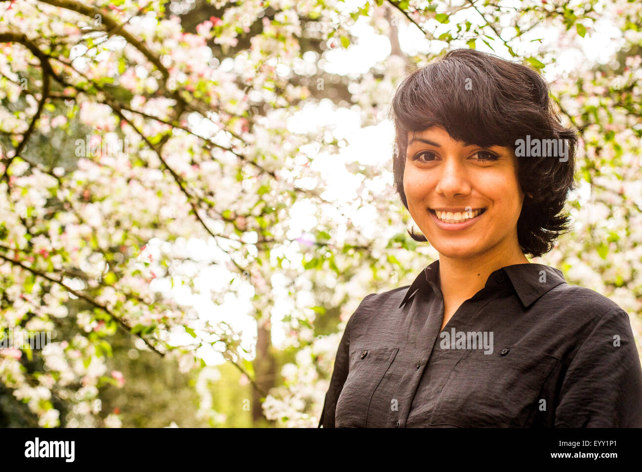 Hispanic Frau lächelnd unter Bäumen Stockfoto