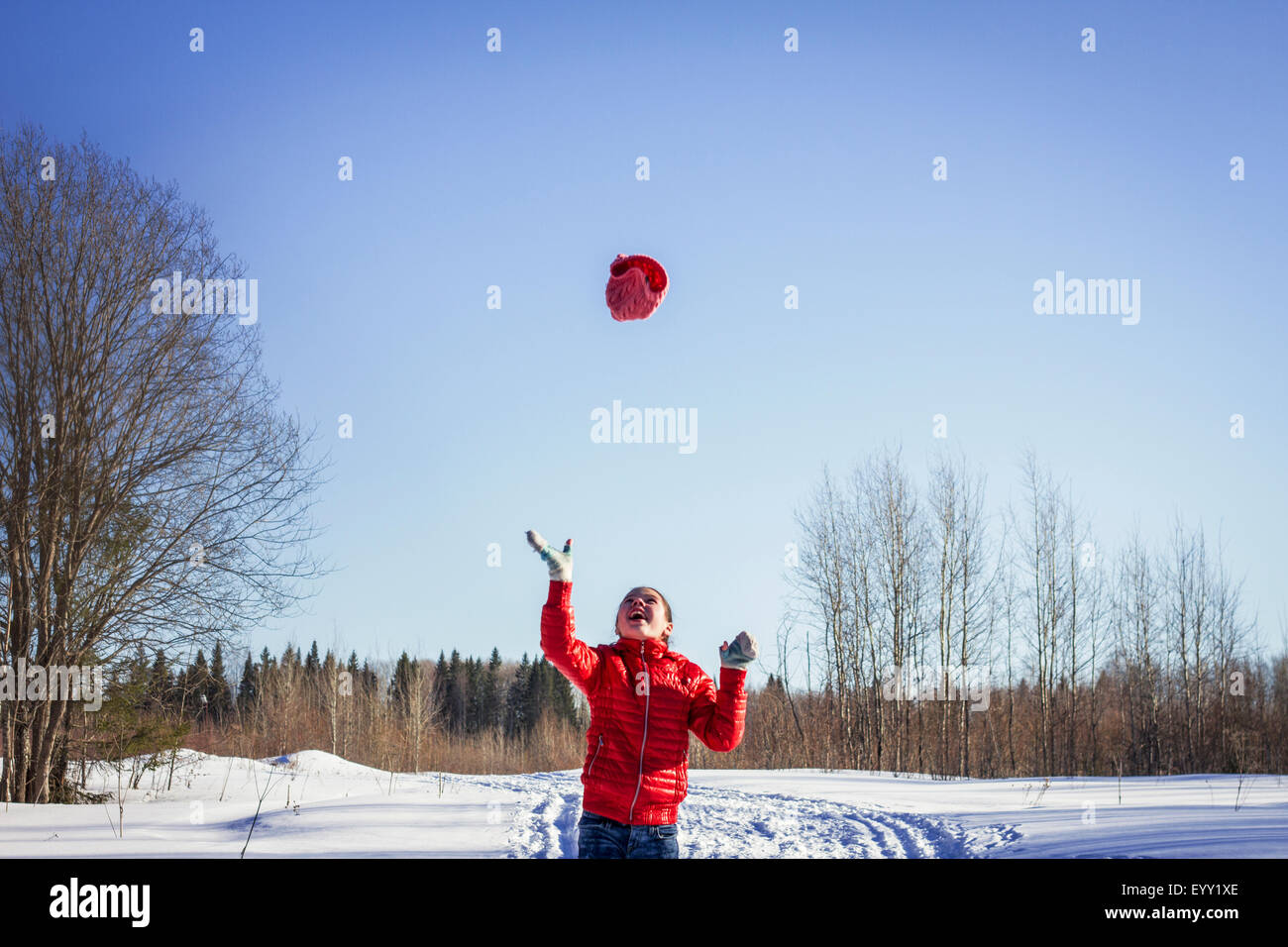 Kaukasische Mädchen werfen Hut in schneebedecktes Feld Stockfoto