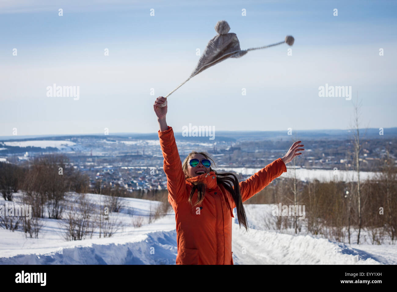 Kaukasische Frau schwingen Hut in verschneiter Landschaft im ländlichen Raum Stockfoto