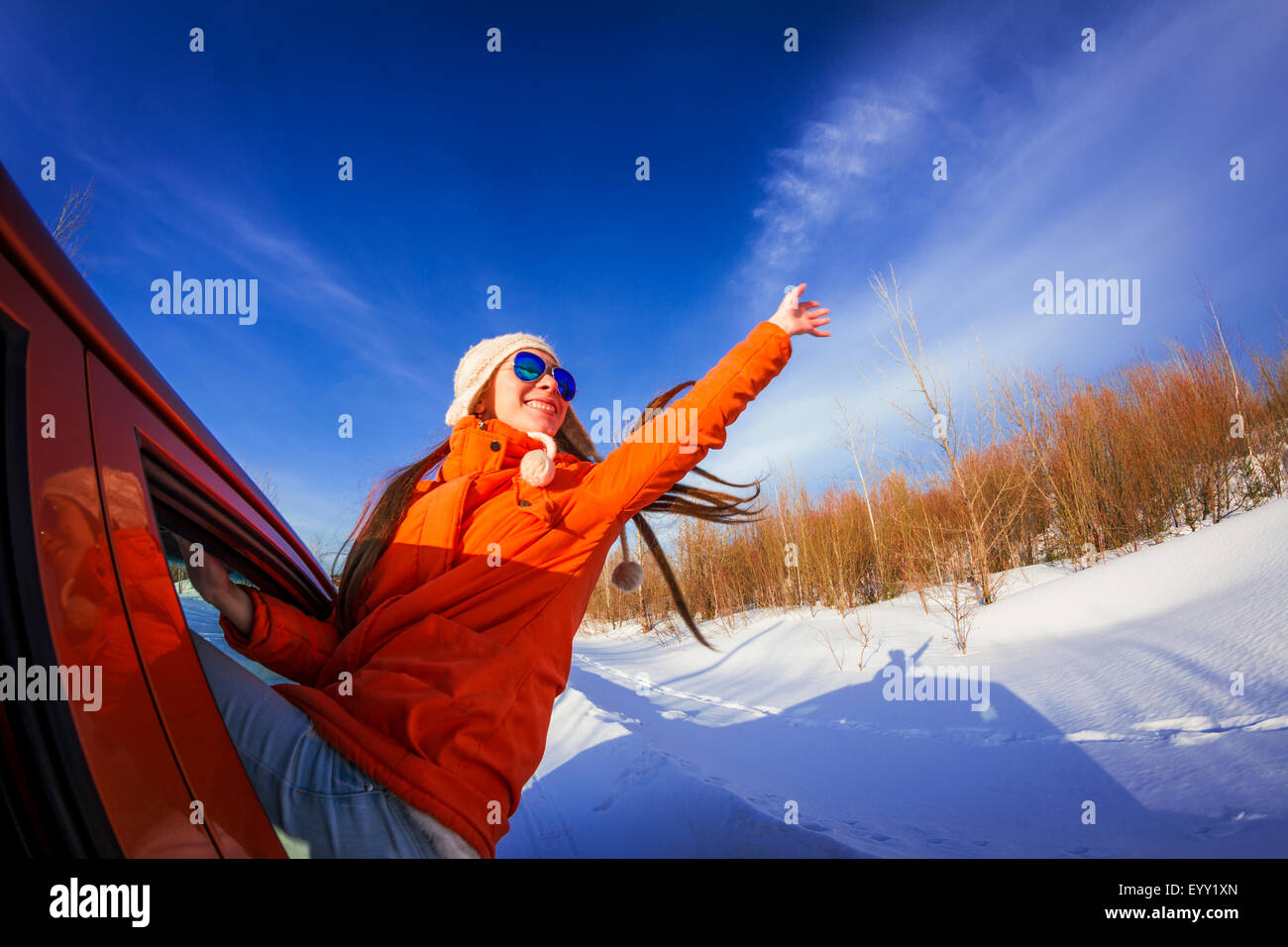 Kaukasische Frau gelehnt, Autofenster in schneebedecktes Feld Stockfoto