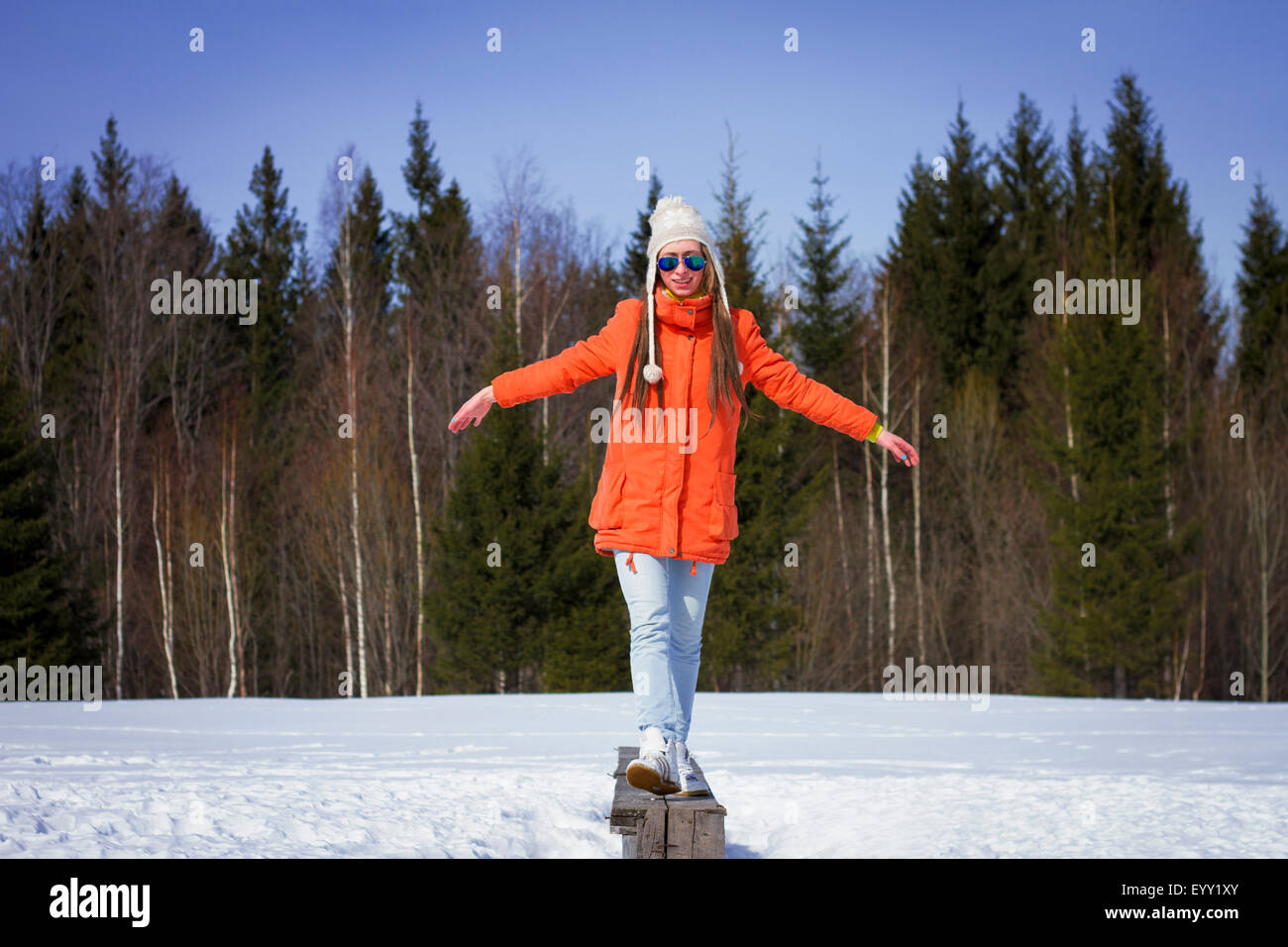 Kaukasische Frau balancieren auf Holzbank in schneebedecktes Feld Stockfoto