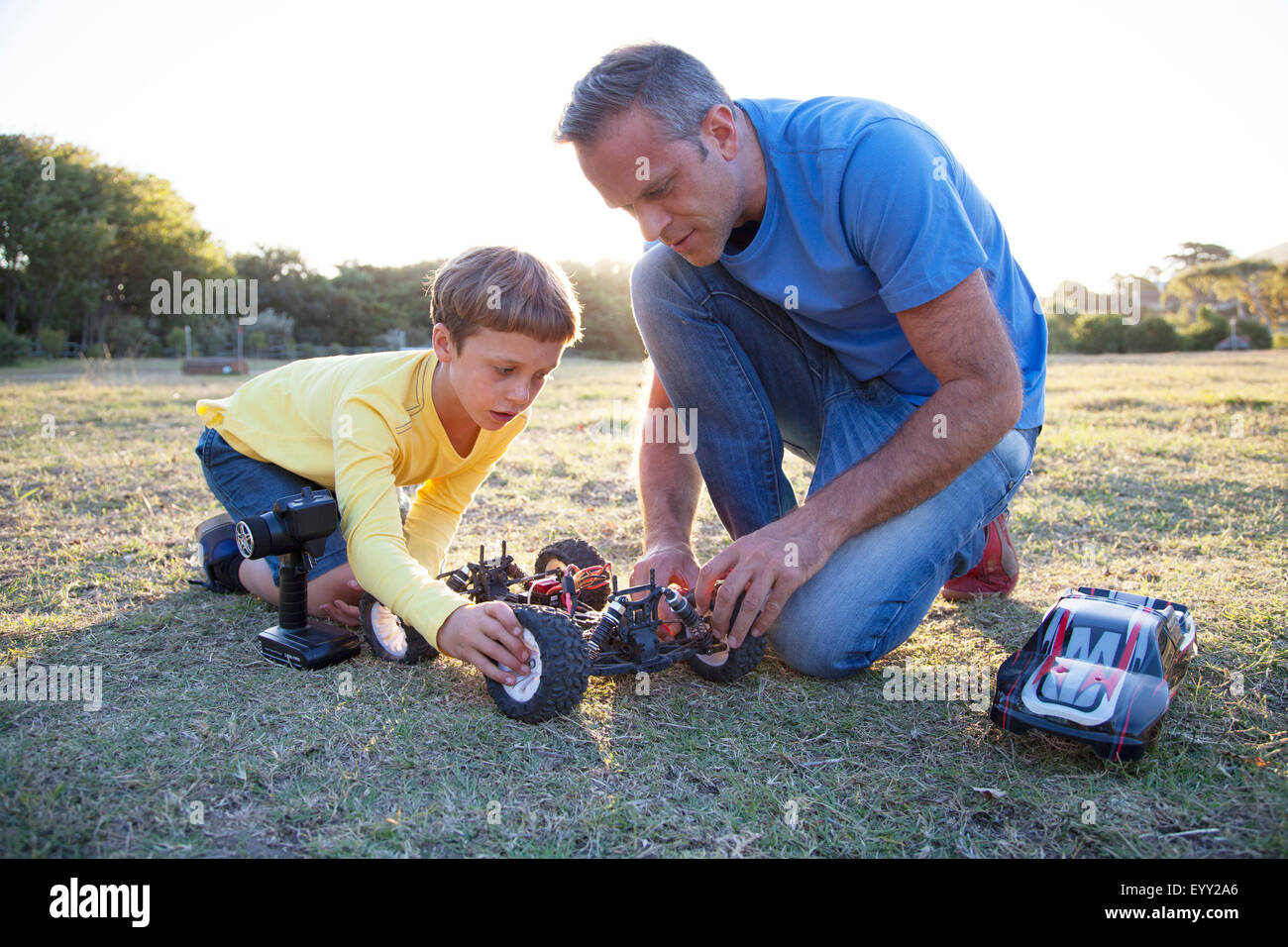 Kaukasische Vater und Sohn spielen mit ferngesteuerten Autos im Feld Stockfoto