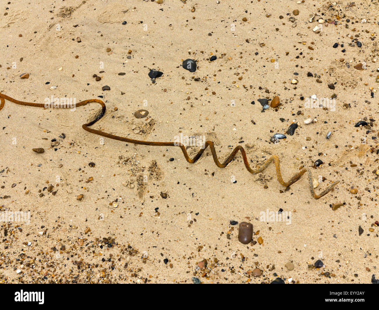 Rostenden Korkenzieher verbogen Metall an einem Strand mit kleinen Kieselsteinen Stockfoto