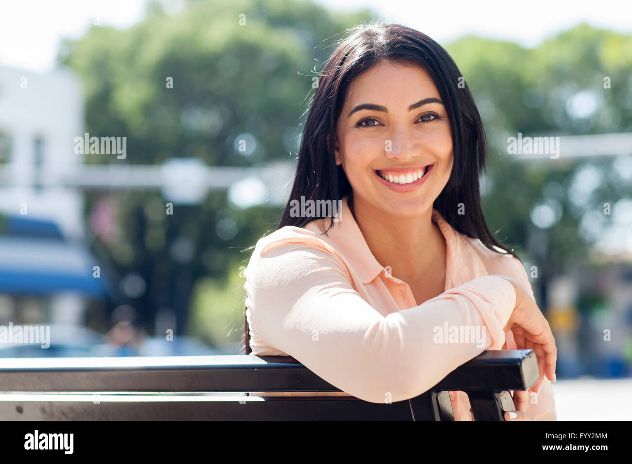 Hispanic Frau lächelnd auf Bank Stockfoto