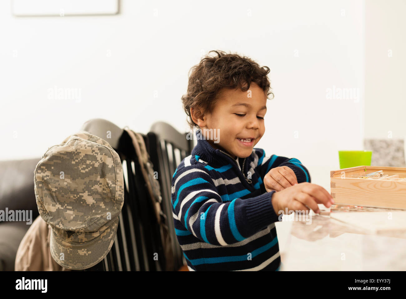 Gemischte Rassen junge spielt am Schalter in der Nähe von Camouflage Kappe Stockfoto