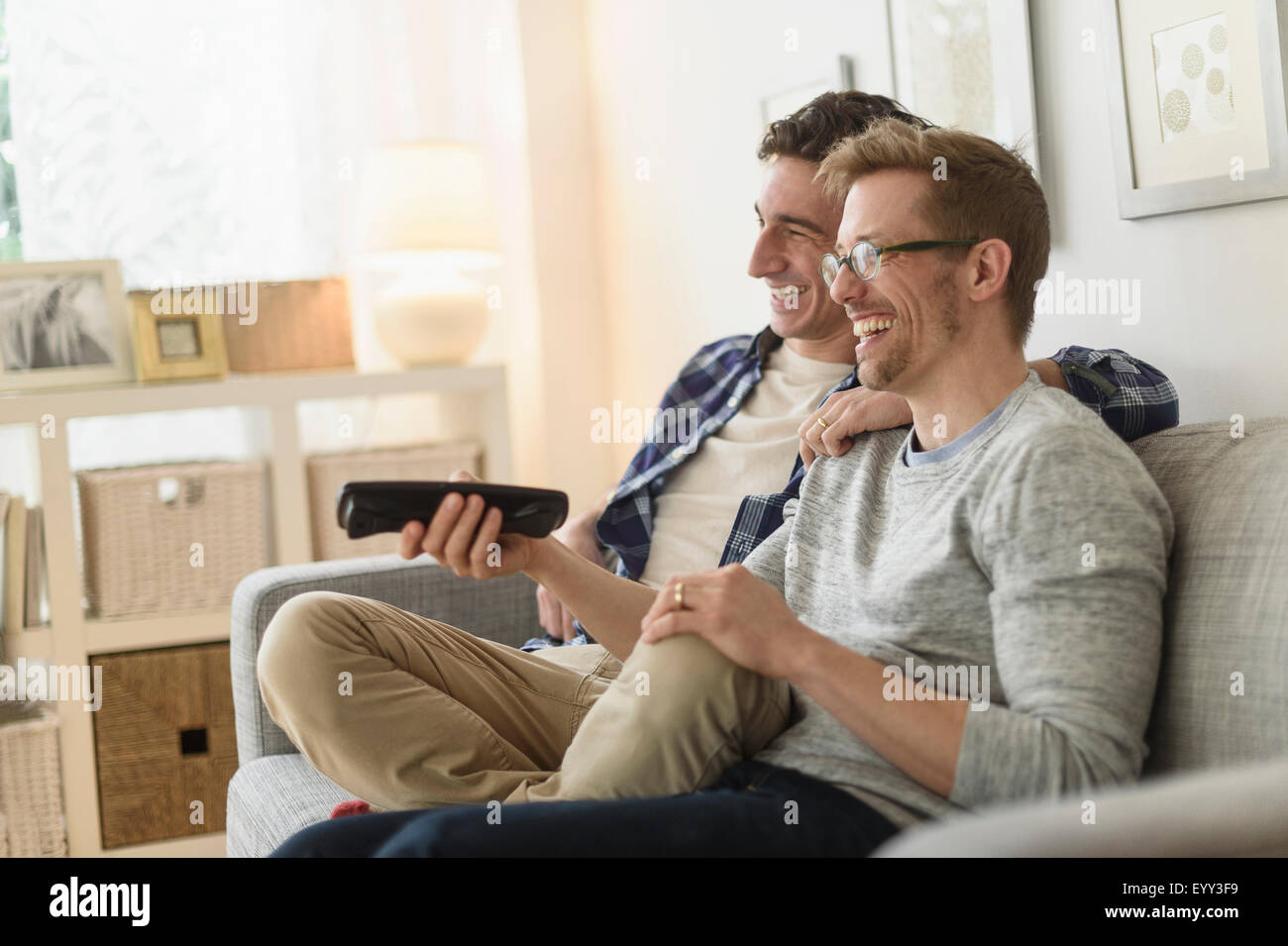 Kaukasische schwules Paar vor dem Fernseher auf sofa Stockfoto