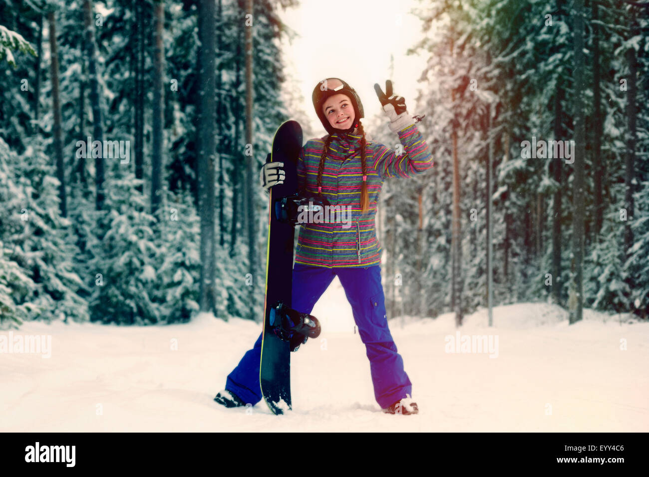 Kaukasische Snowboarder machen Friedenszeichen im verschneiten Wald Stockfoto