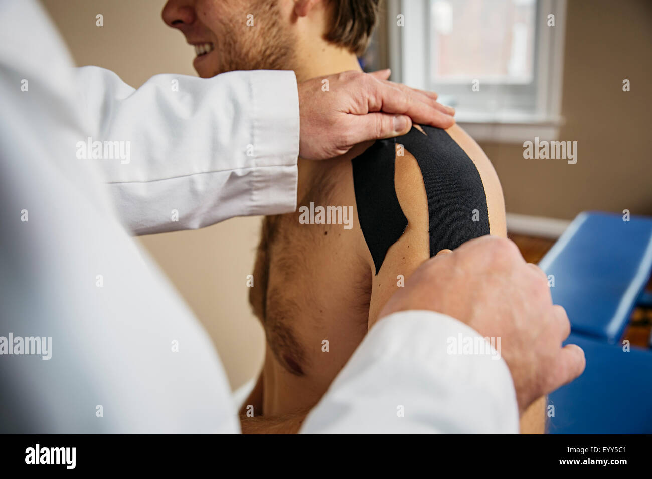 Kaukasische Arzt Klebeband an der Schulter des Patienten Stockfoto