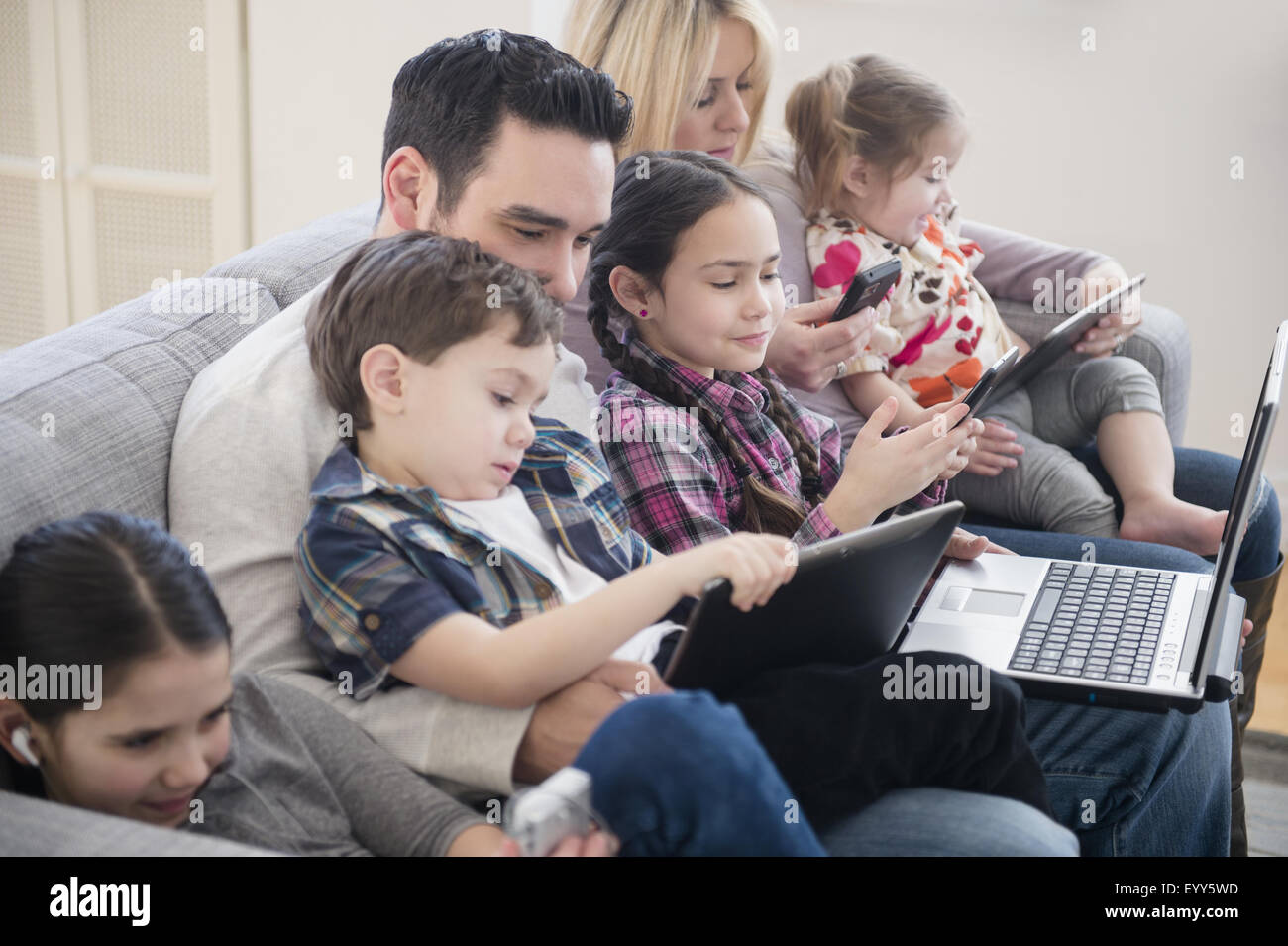 Kaukasische Familie mit Hilfe von Technologie auf sofa Stockfoto