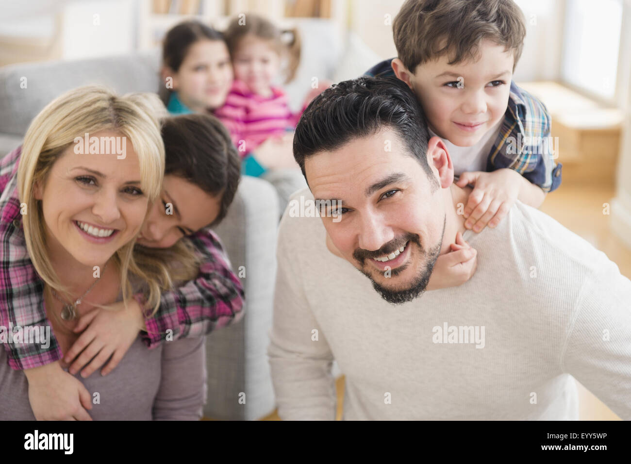 Huckepack-kaukasische Eltern mit Kindern im Wohnzimmer Stockfoto