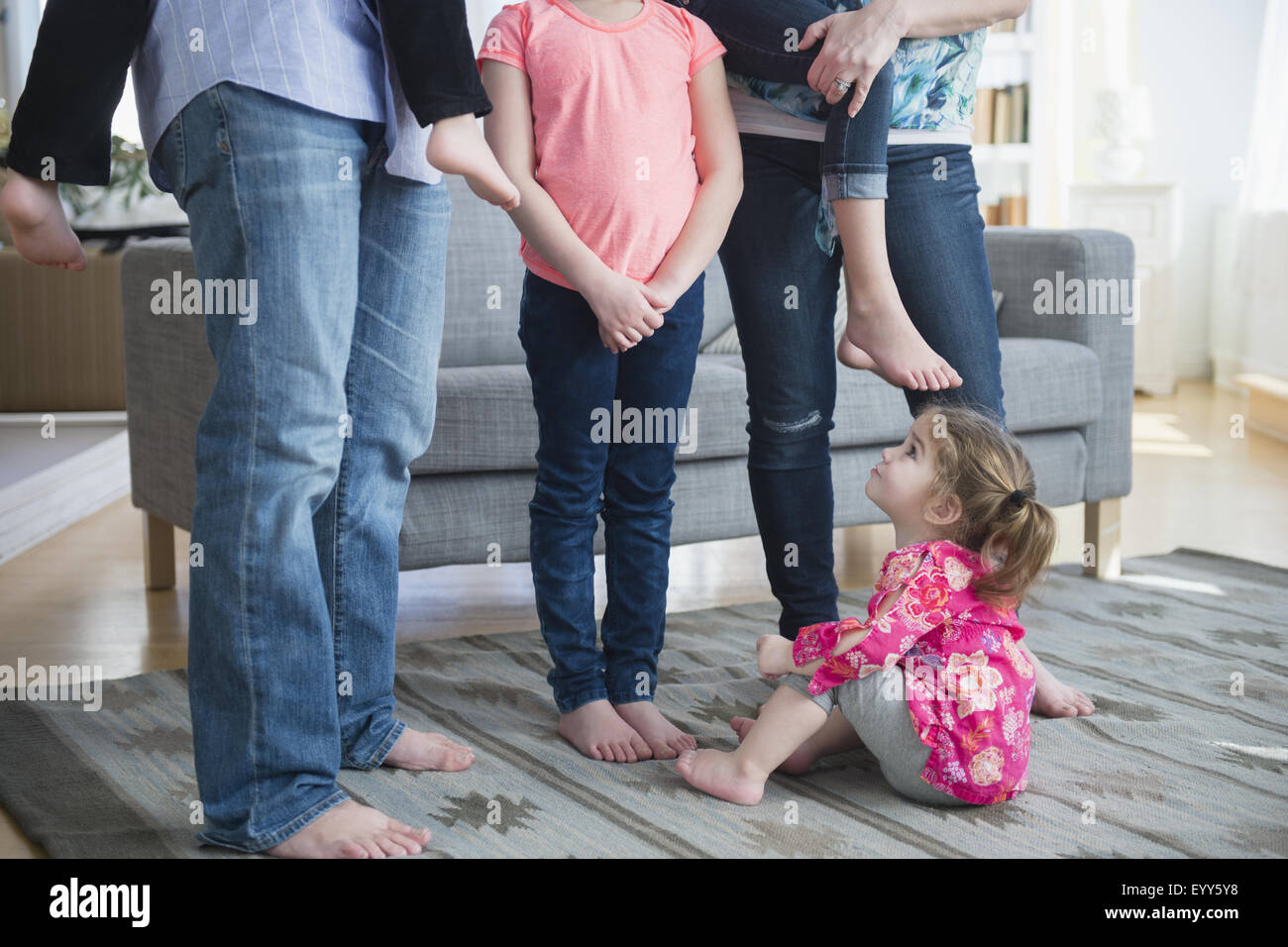 Kaukasische Mädchen sitzen unter Familie im Wohnzimmer Stockfoto