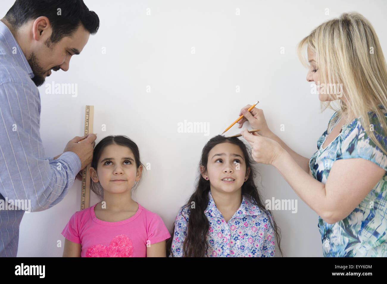 Kaukasische Eltern Messung der Höhe der Töchter an Wand Stockfoto
