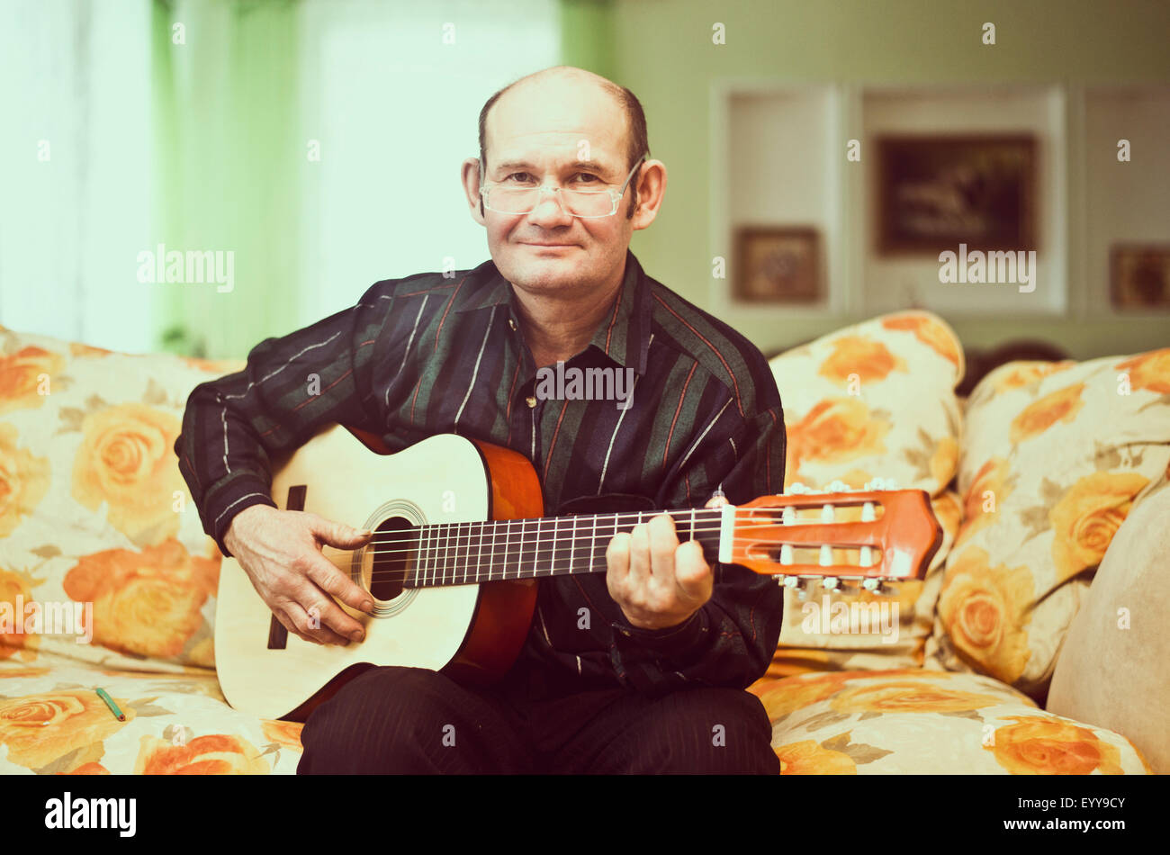 Kaukasischen Mann spielt Gitarre auf sofa Stockfoto