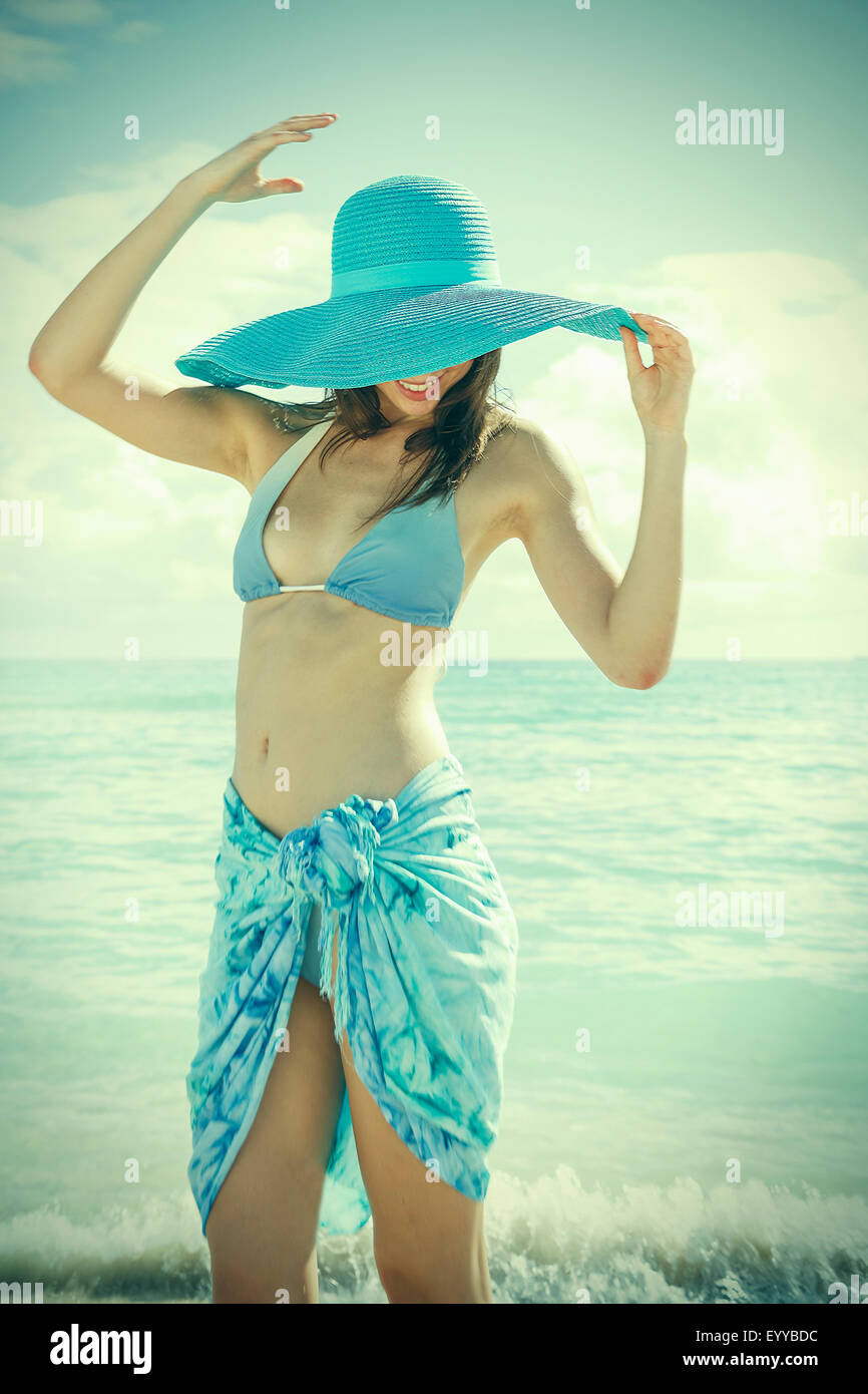 Kaukasische Frau trägt Bikini und Sonnenhut am Strand Stockfoto