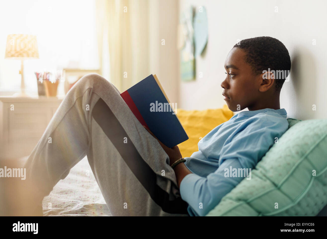 Schwarzer Junge Buch auf Bett Stockfoto