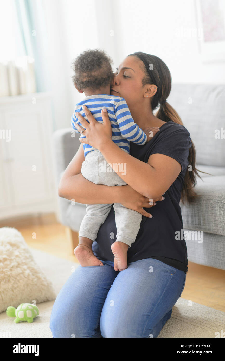 Mischlinge Mutter küssen Baby Sohn im Wohnzimmer Stockfoto