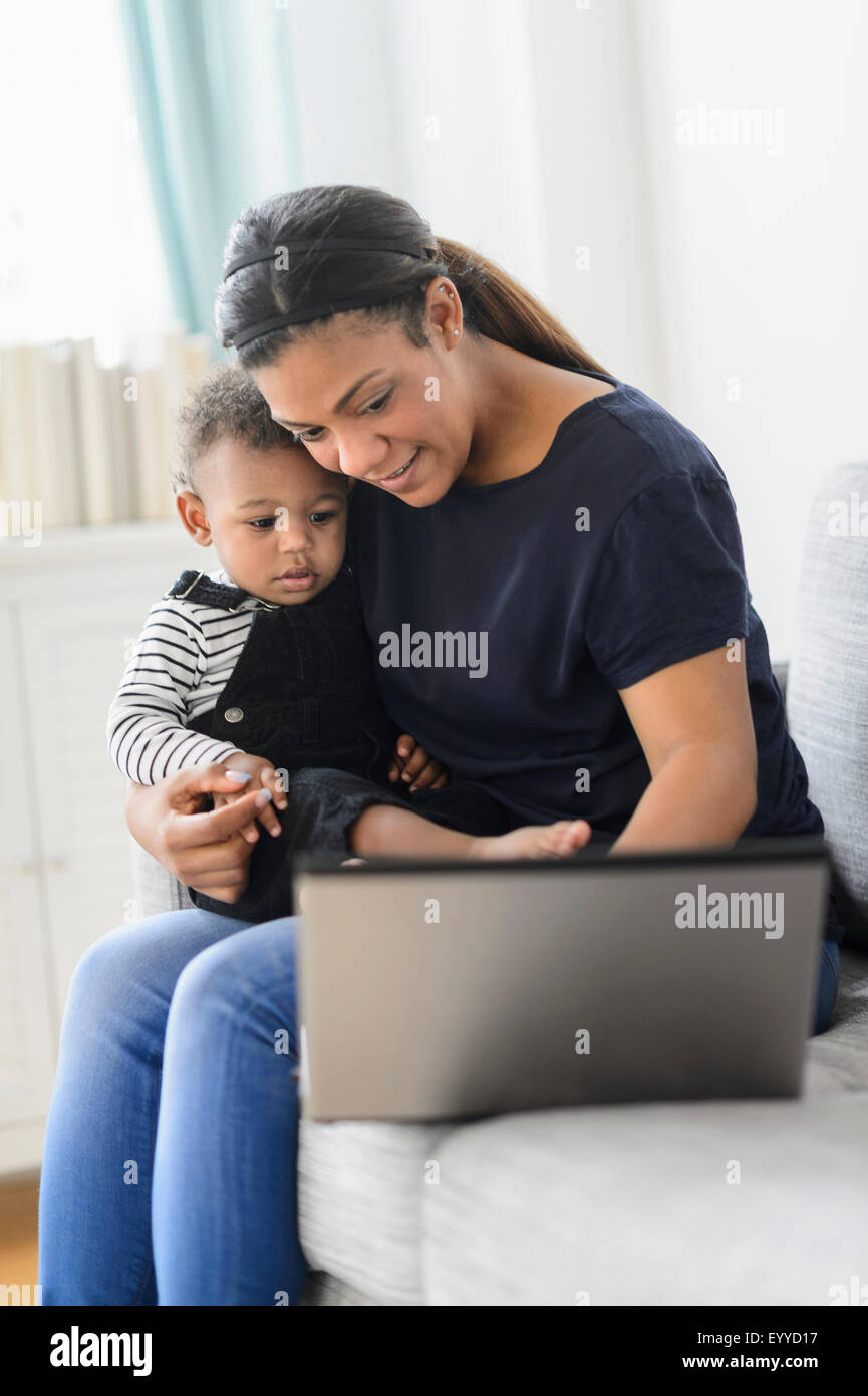 Mischlinge Mutter mit Laptop mit Baby Sohn im Wohnzimmer Stockfoto