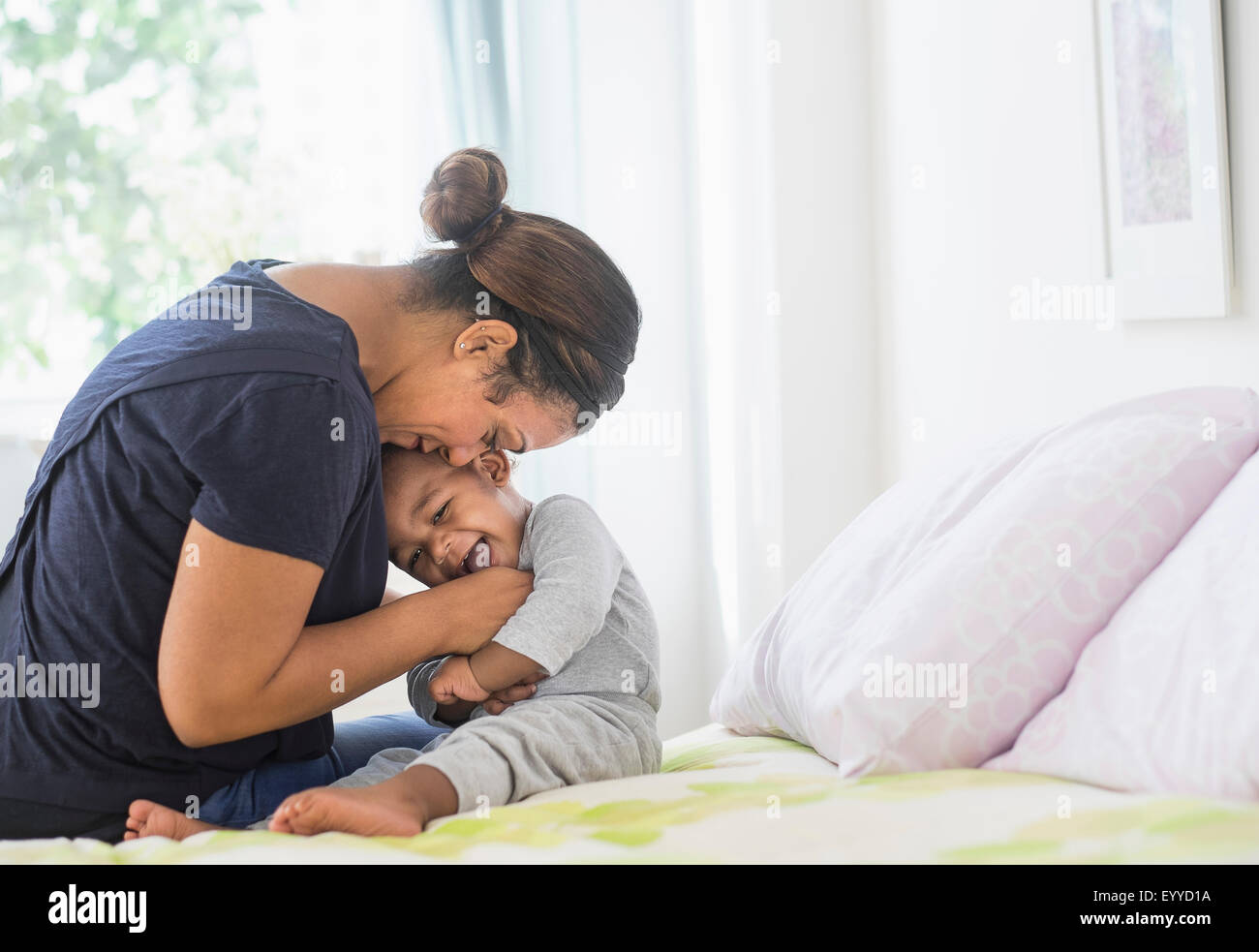 Mischlinge Mutter kitzeln Baby Sohn auf Bett Stockfoto