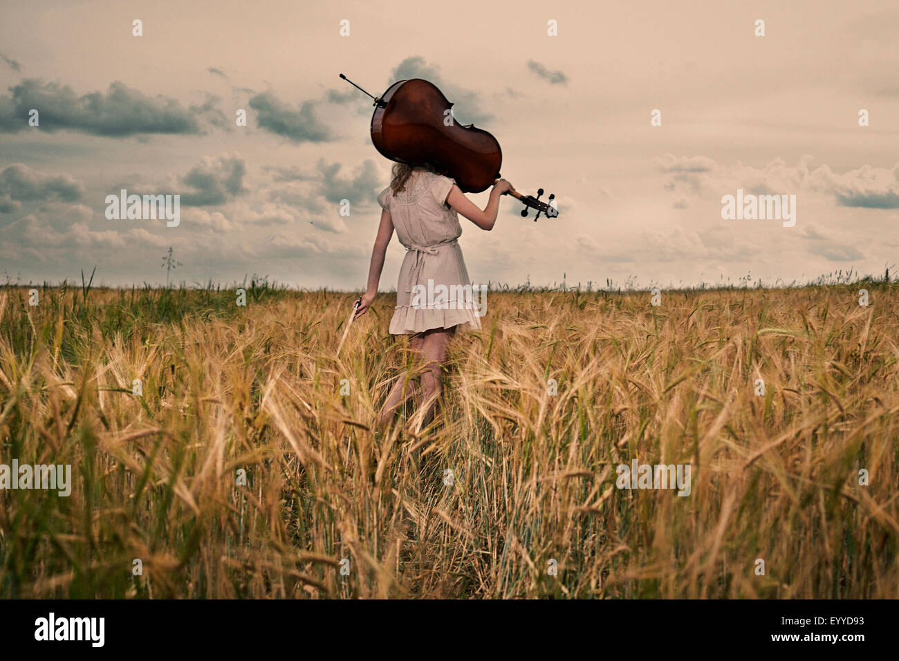 Kaukasische Mädchen tragen Cello auf Schulter in ländlichen fieldCaption Stockfoto