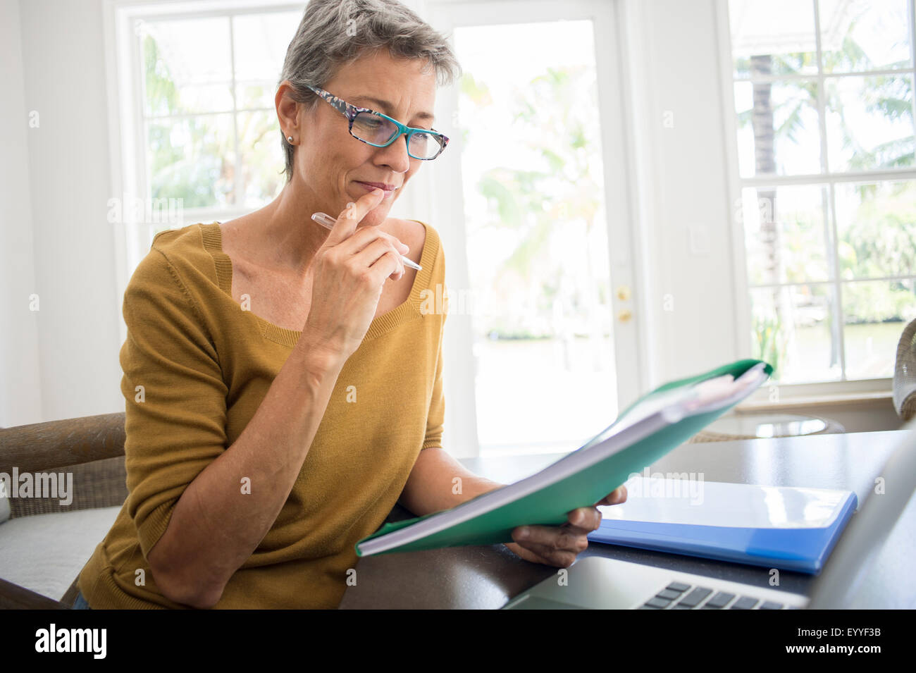 Frau liest Ordner am Schreibtisch im Wohnzimmer Stockfoto