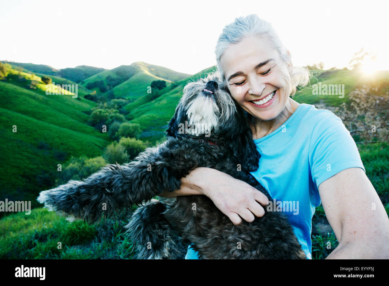 Älteren kaukasischen Frau umarmt Hund auf ländlichen Hügel Stockfoto