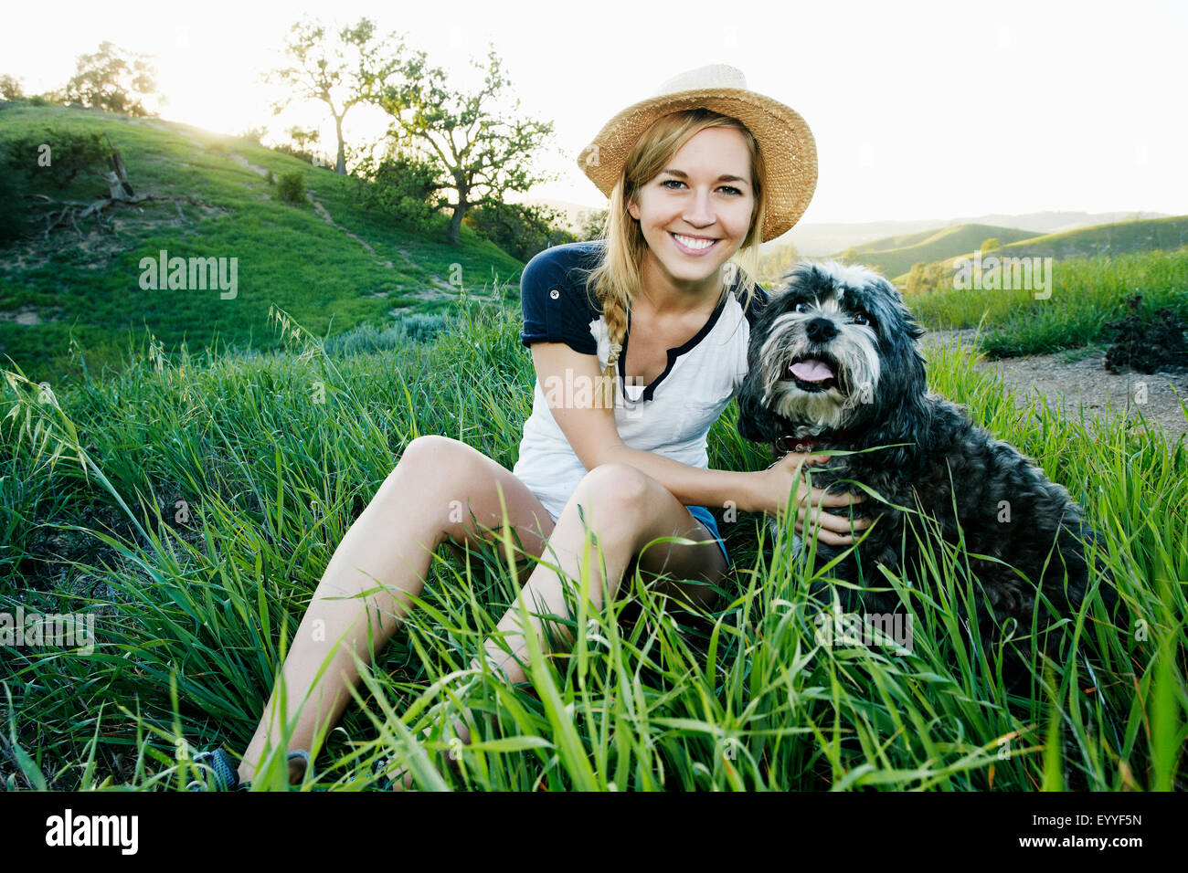 Kaukasische Frau Petting Hund im Feld Stockfoto