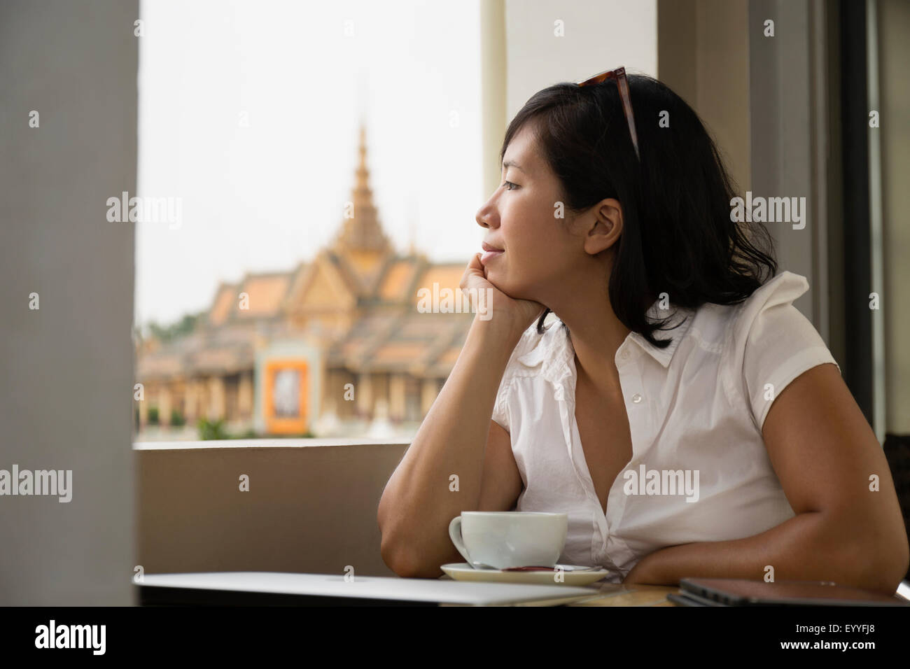 Asiatische Frau schaut aus Café Fenster, Phnom Penh, Kambodscha Stockfoto