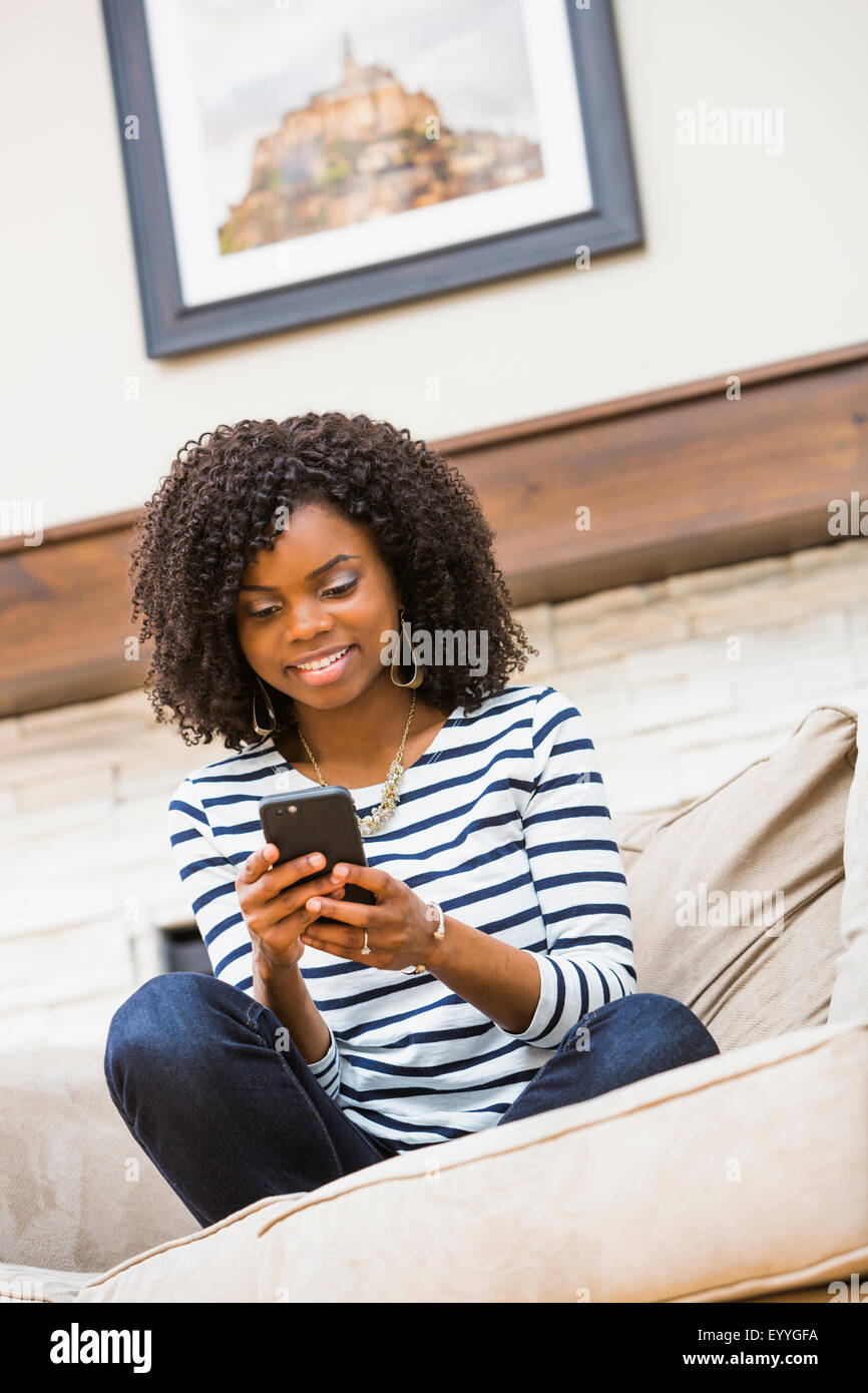 Schwarze Frau mit Handy auf sofa Stockfoto