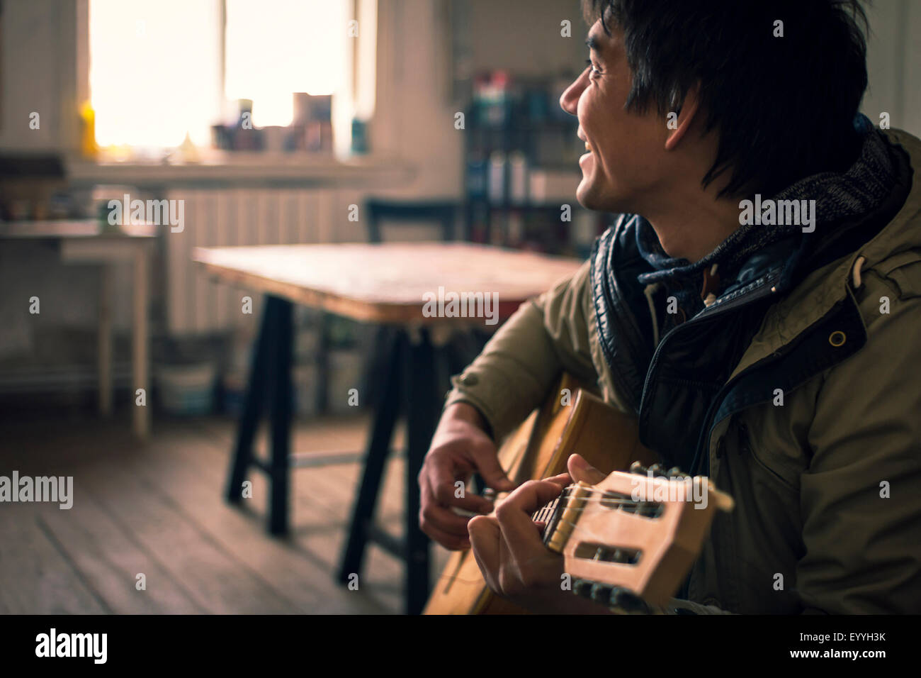 Asiatischer Mann Gitarre spielen im Innenbereich Stockfoto