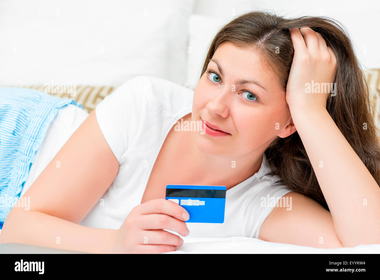 Porträt eines Mädchens mit einer Kreditkarte, die auf einem Bett liegend Stockfoto