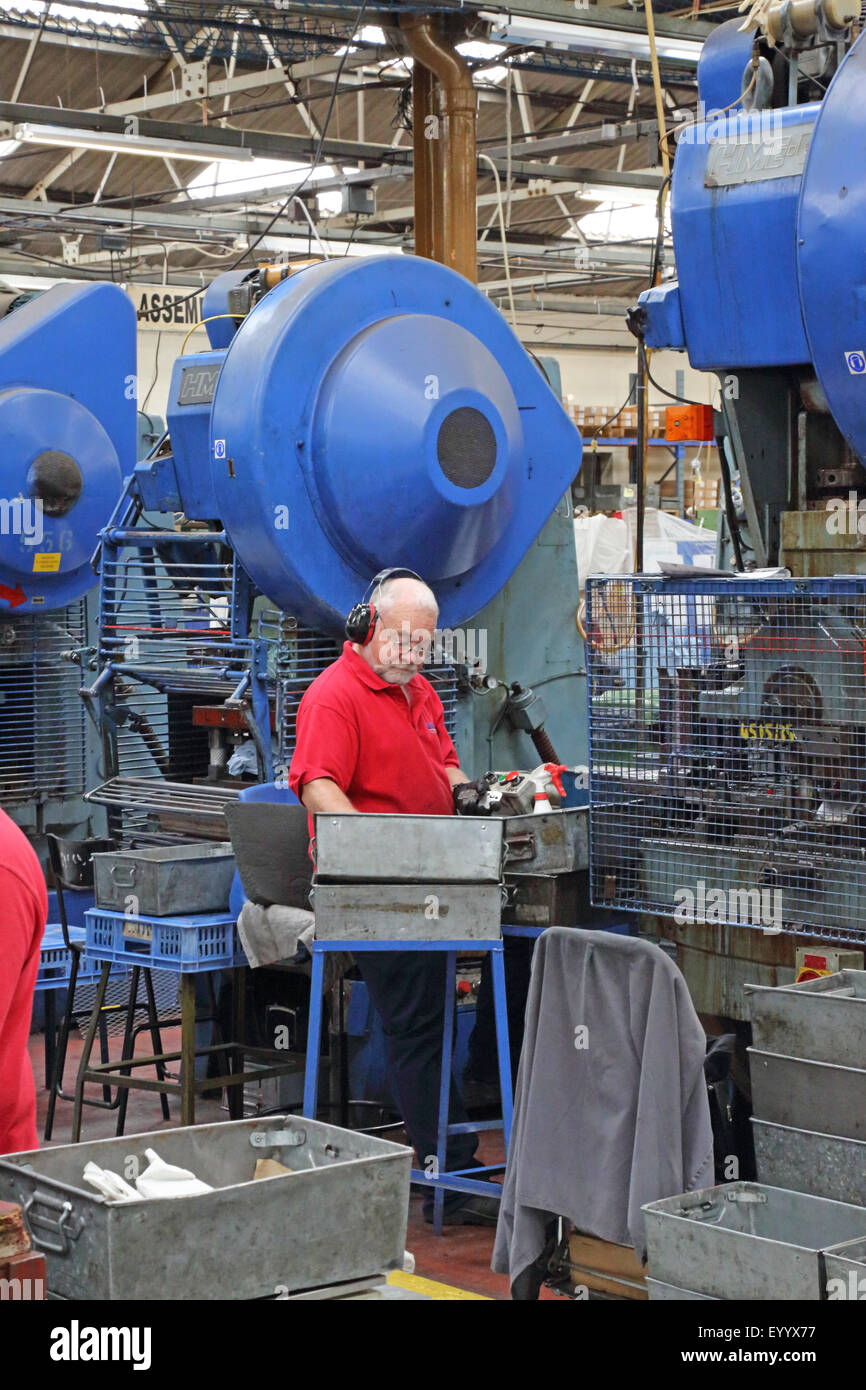 Eine ältere männliche Arbeiter produziert Metallteile für die Bauindustrie, mit einem großen Stahl Pressmaschine Stockfoto