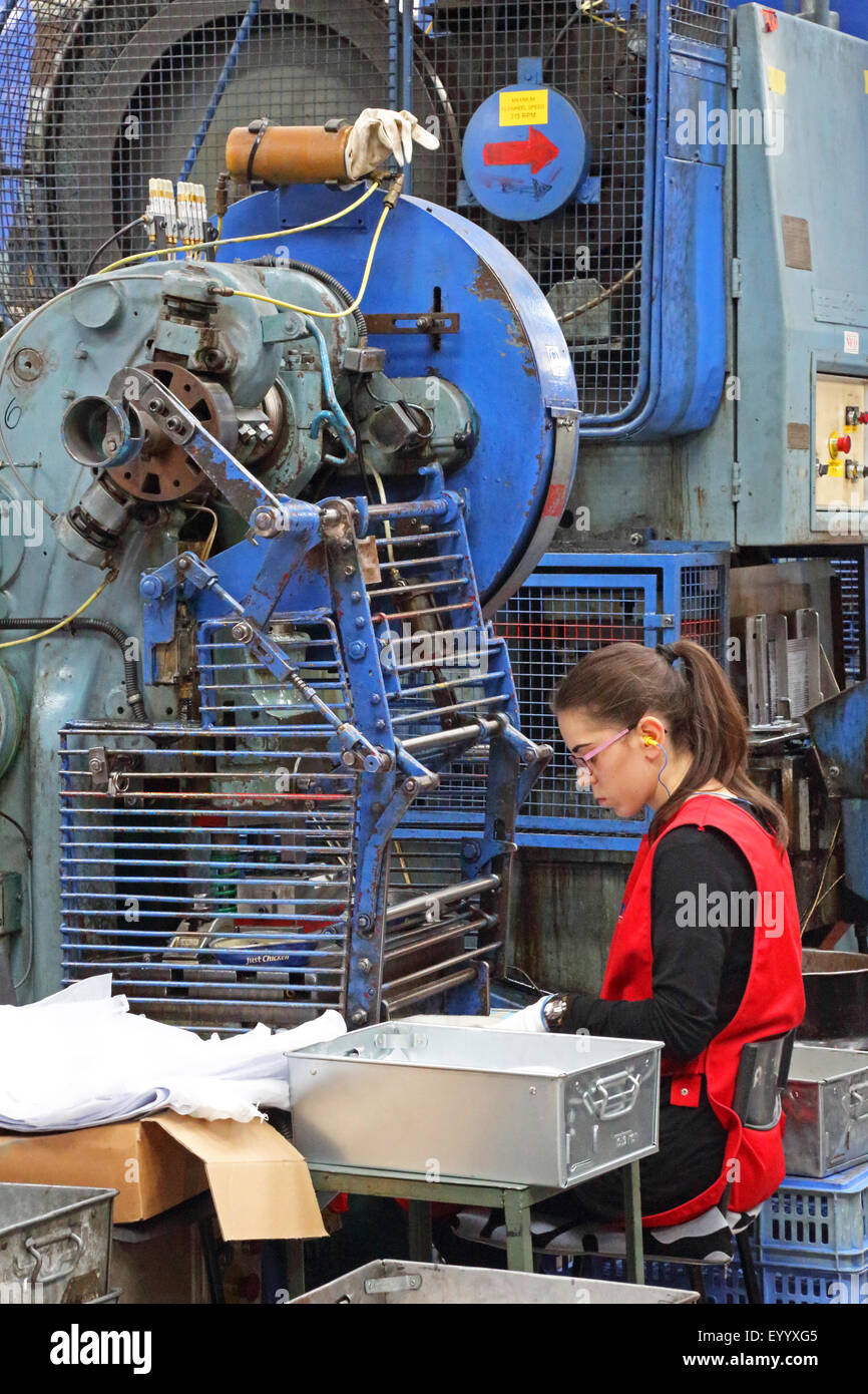 Eine junge Arbeitnehmerin macht Metallkomponenten für die Bauindustrie, mit einem großen Stahl Pressmaschine Stockfoto