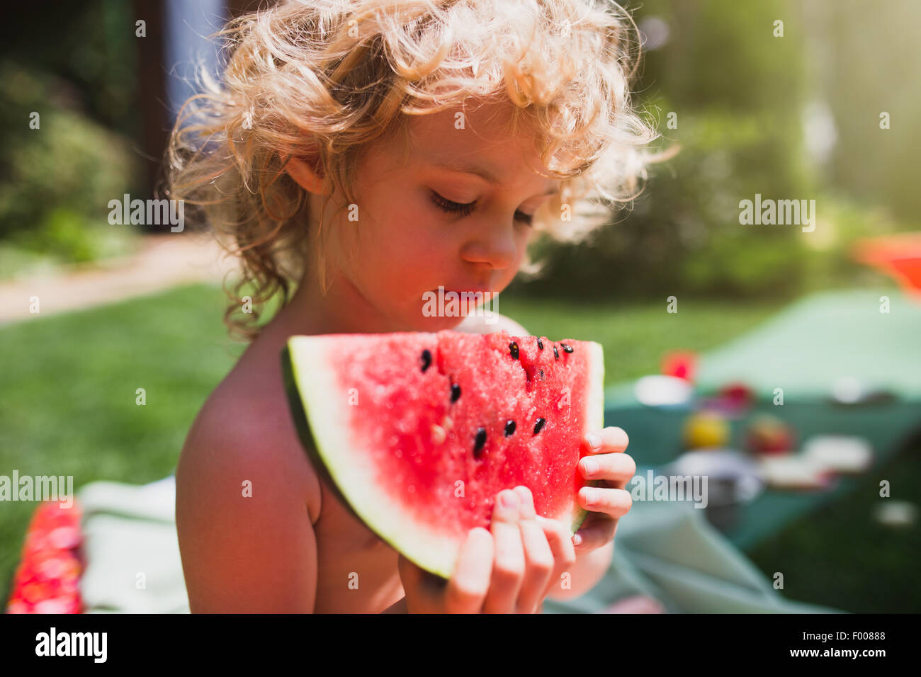 Kleine Mädchen essen Wassermelone auf dem Rasen im Sommer Stockfoto