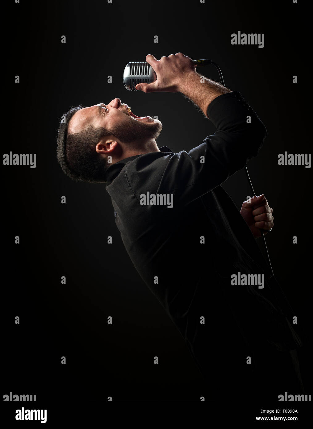Sänger mit Mikrofon vor einem dunklen Hintergrund Stockfoto