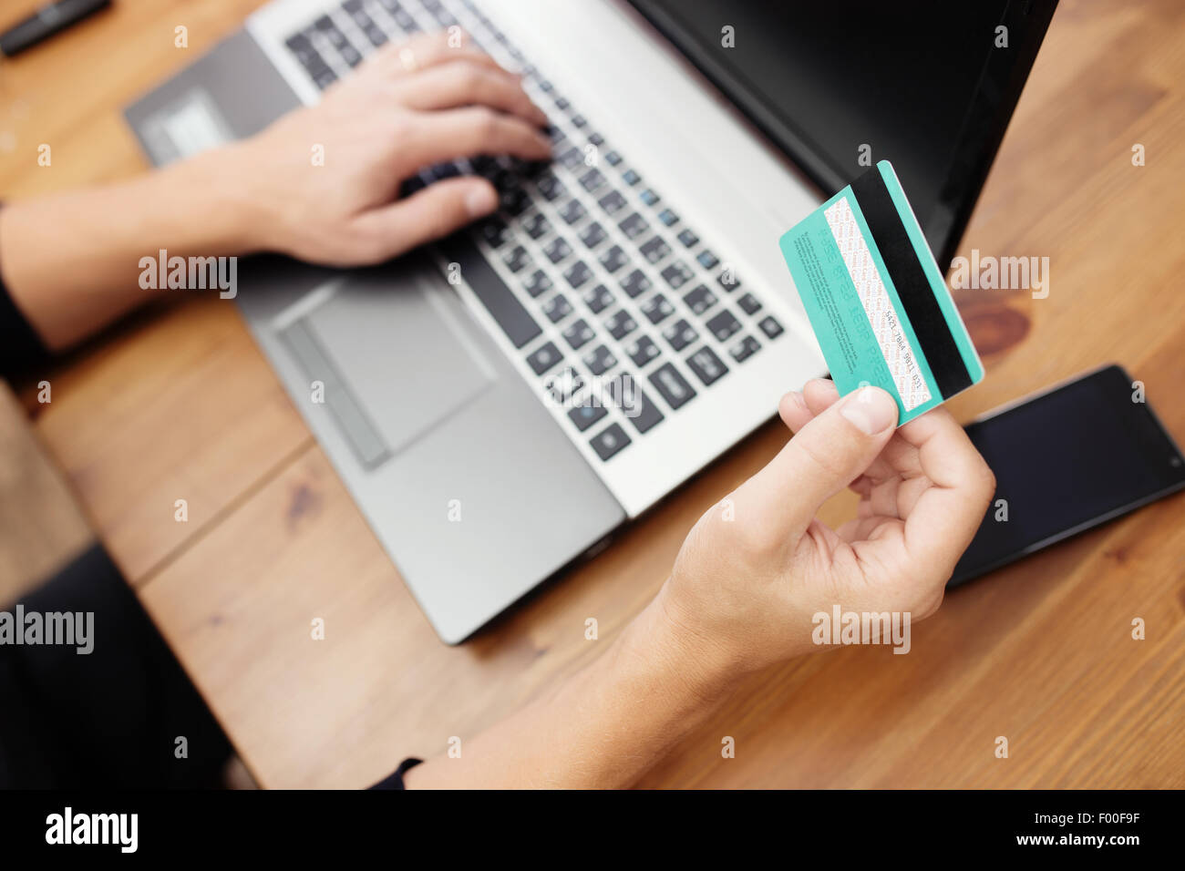 Mann hält Kreditkarte in der hand und die Eingabe Sicherheitscode mit Laptop-Tastatur Stockfoto