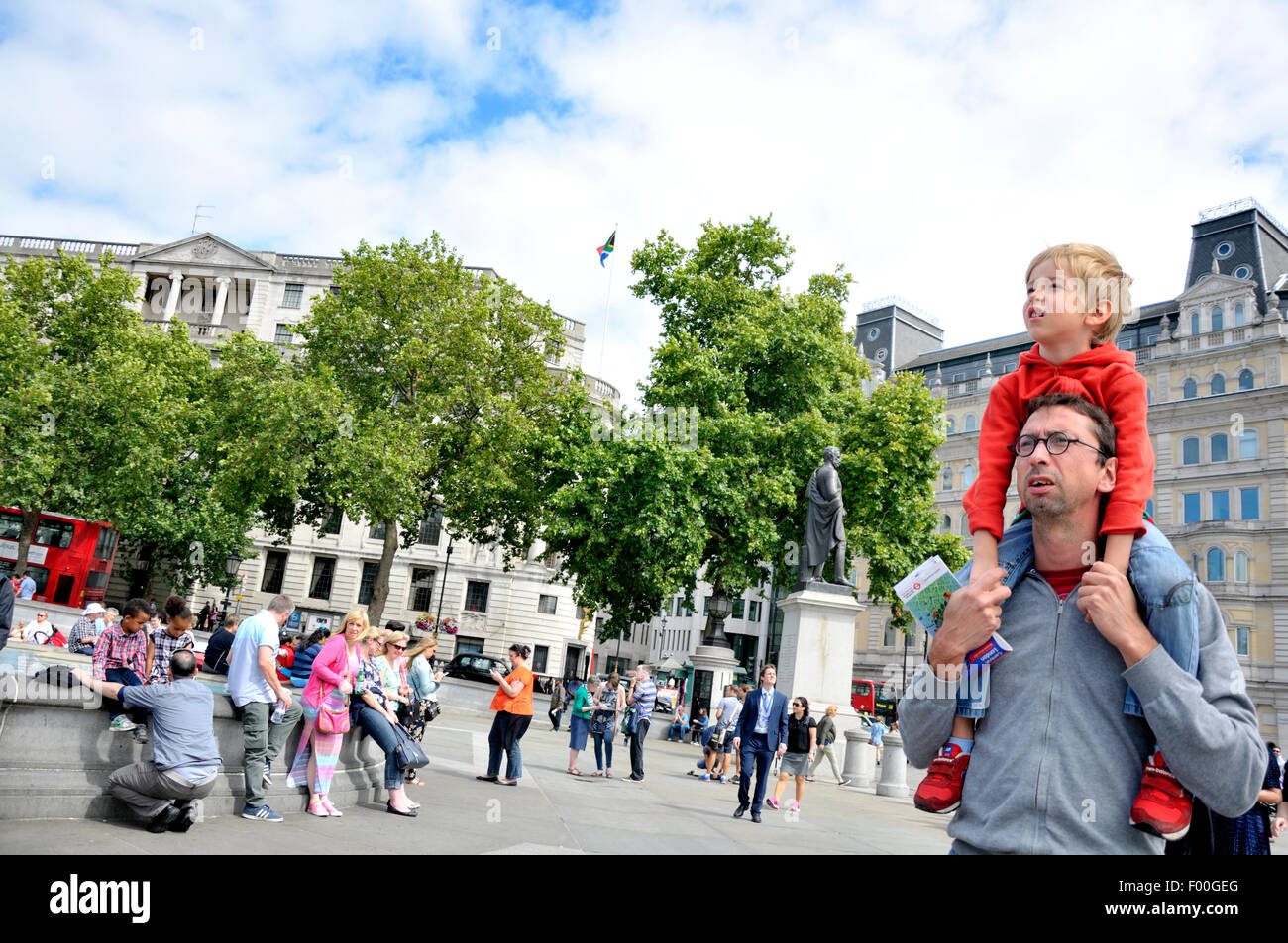 London, England, Vereinigtes Königreich. Junge sitzt auf seines Vaters Schultern auf dem Trafalgar Square Stockfoto