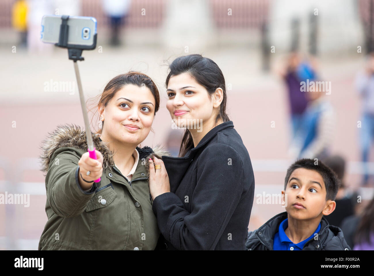 Asiatische Frauen Pose für ein Selbstportrait mit einem Handy und einem Selfie stick außerhalb der Buckingham Palace, London, UK. Stockfoto