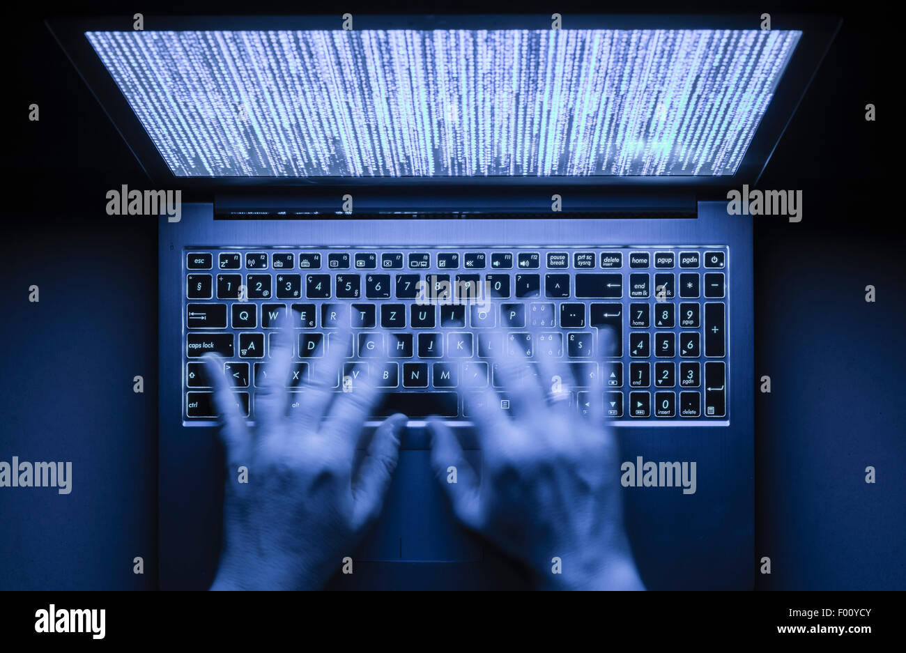 Hände werden auf einem Laptop-Computer in der Dunkelheit mit beleuchtete Tastatur und mystische Programmcode auf dem Bildschirm tippen. Stockfoto