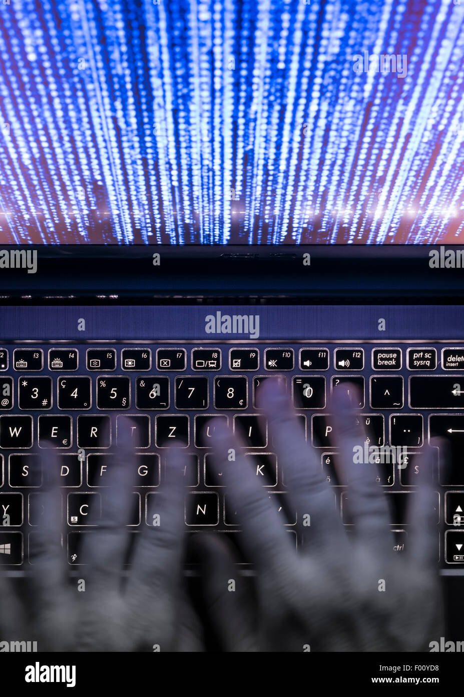 Hände werden auf einem Laptop-Computer in der Dunkelheit mit beleuchtete Tastatur und mystische Programmcode auf dem Bildschirm tippen. Stockfoto