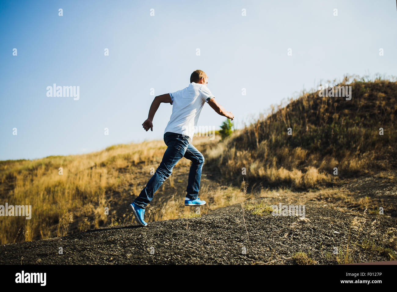 Junger Mann in Freizeitkleidung bergauf laufen Stockfoto
