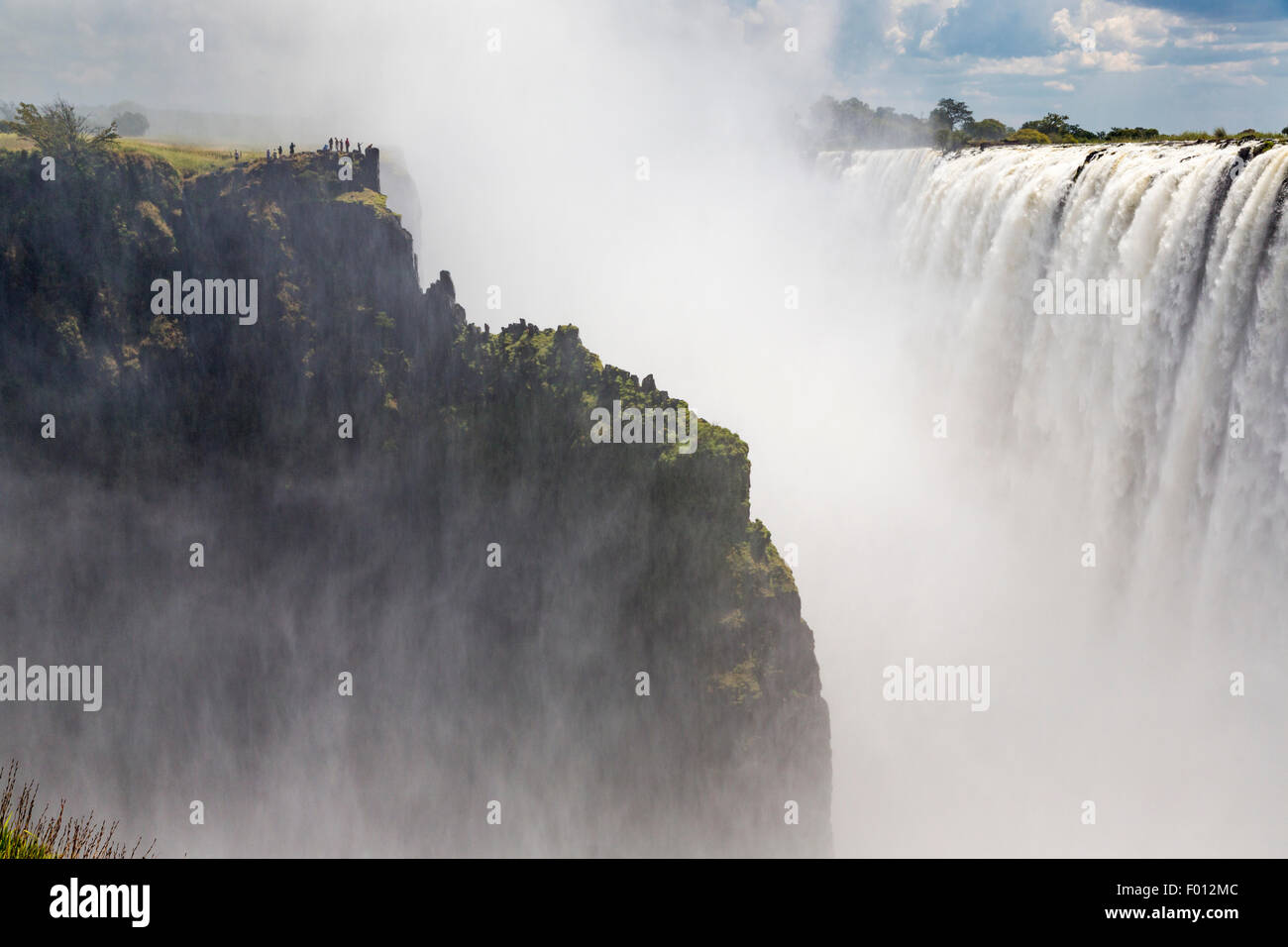 Viktoriafälle vom Mosi-Oa-Tunya Nationalpark in Sambia. Besucher auf der Klippe gegenüber sind auf der Zimbabwe Seite Stockfoto