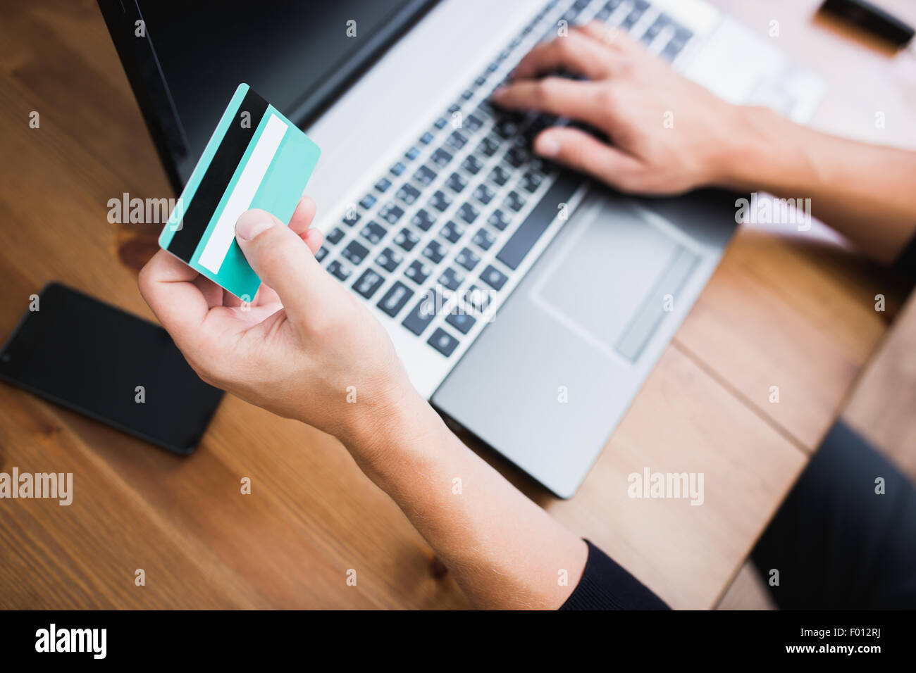 Mann hält eine Kreditkarte und eingeben. Online-Einkaufen im Internet mit einem laptop Stockfoto