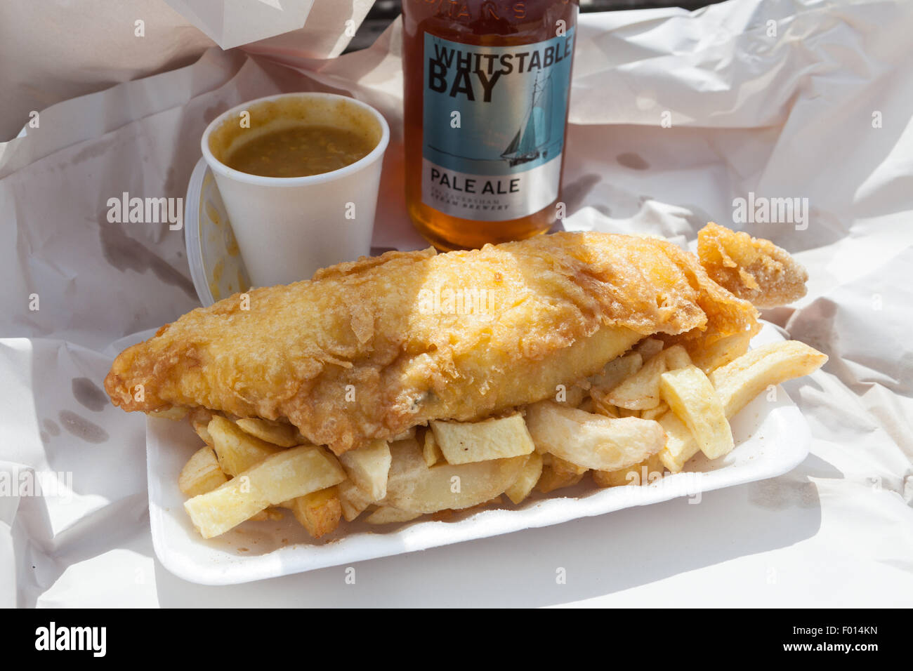 Take-away Fish &amp; Chips mit Currysauce und Whitstable Pale Ale. Stockfoto