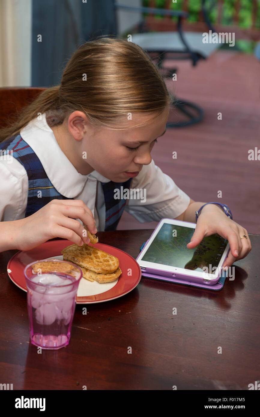 Young Girl (elf Jahre alt) mit iPad während Essen Frühstück.  HERR Stockfoto