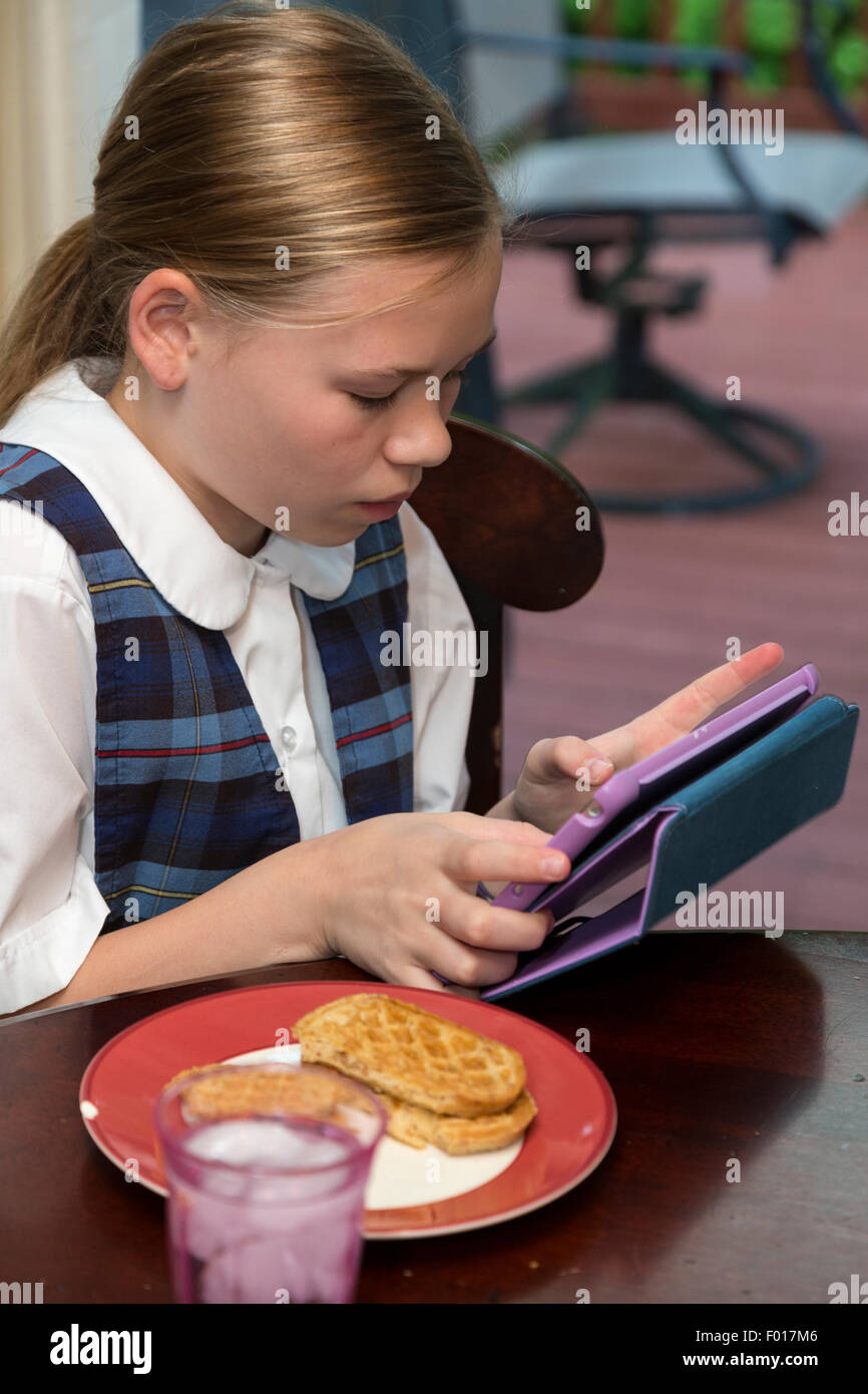 Young Girl (elf Jahre alt) mit iPad während Essen Frühstück.  HERR Stockfoto