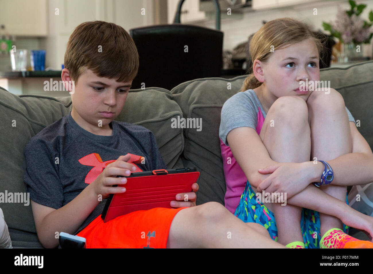 Bruder und Schwester Aufmerksamkeit geteilt zwischen iPad und Fernsehen.  HERR Stockfoto